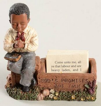 Figurine of a boy praying beside a sign about promises and prayers.