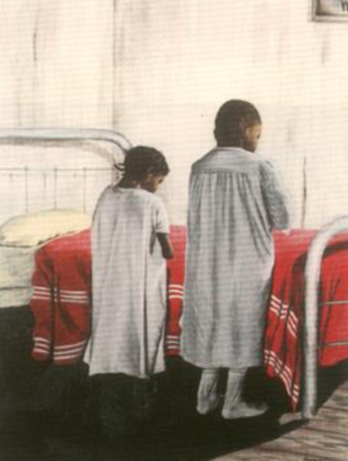 Two children standing by a hospital bed dressed in traditional attire.